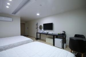 a bedroom with two beds and a desk with a television at VIEW Hotel Geoje in Geoje 