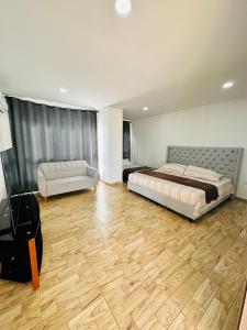 Juan de Acosta的住宿－Villa Sol Deluxe，一间卧室配有一张床和一张沙发,铺有木地板