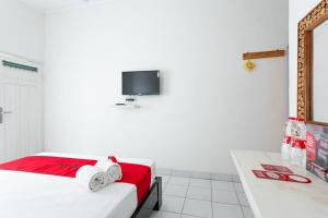 a white room with a bed and a tv on the wall at RedDoorz near Grojogan Sewu Tawangmangu in Karanganyar