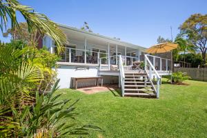 a house with a staircase and an umbrella in the yard at Nelson's Landing - Pet Friendly in Jervis Bay in Vincentia