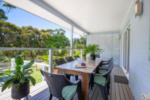 an outdoor deck with a wooden table and chairs at Nelson's Landing - Pet Friendly in Jervis Bay in Vincentia