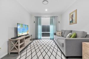 OSPREY ISLAND RETREAT في Banksia Beach: غرفة معيشة مع أريكة رمادية وتلفزيون
