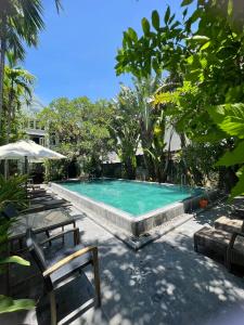 a swimming pool with two chairs and an umbrella at East West Villa in Hoi An