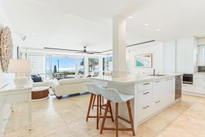a kitchen with white cabinets and a table and chairs at Beachfront luxury, Hastings Street in Noosa Heads