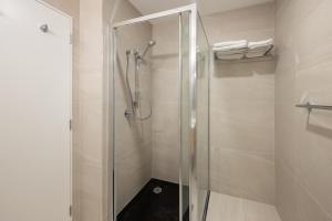 a shower with a glass door in a bathroom at Manha Hotel Auckland Airport in Auckland