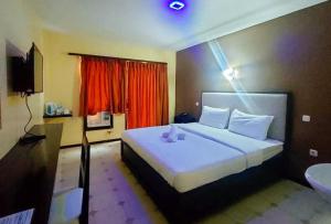 - une chambre avec un grand lit blanc et une télévision dans l'établissement RedDoorz at Carlton-Martin Hotel Masbate City, à Cangbaliguia