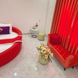 a bedroom with a red bed and a chair and flowers at Happy 2 Hotel Bình Dương in Bến Cát