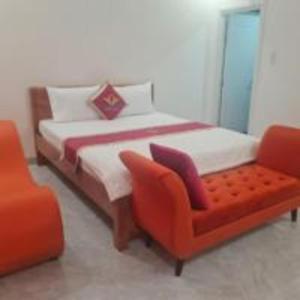 a bedroom with a bed and a orange chair at Happy 2 Hotel Bình Dương in Bến Cát