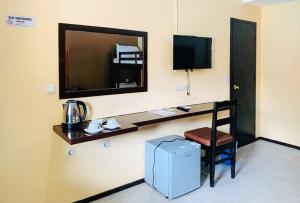 Cette chambre comprend un bureau avec une télévision et une chaise. dans l'établissement RedDoorz at Carlton-Martin Hotel Masbate City, à Cangbaliguia