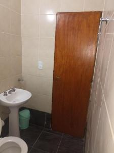 een badkamer met een toilet en een houten deur bij Atardecer Santiagueño in Fernández