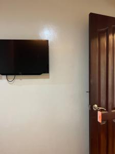 a flat screen tv on a wall next to a door at Inside Room Inn in Tagum