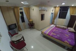 1 dormitorio con 1 cama de color púrpura y sillas en Utama Syariah en Pekanbaru