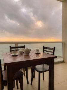 uma mesa e cadeiras de madeira com vista para o oceano em MaSa Beach Front Apartment Uswetakeiyawa em Ja-Ela