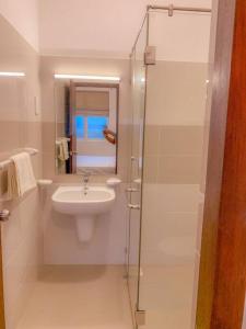 a white bathroom with a sink and a shower at MaSa Beach Front Apartment Uswetakeiyawa in Ja-Ela