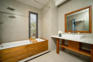 een badkamer met een bad, een wastafel en een spiegel bij Palm Boutique Village - STAY 24H in Hội An