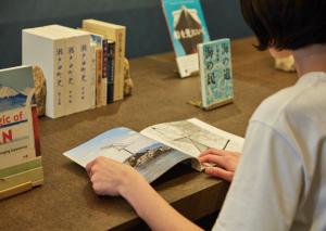 a young boy reading a book at a table with books at yubune in Onomichi