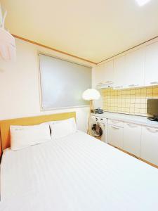 a bedroom with a white bed and a kitchen at Sarang Guesthouse Dongdaemun in Seoul
