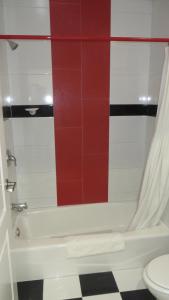 łazienka z białą wanną i czerwoną ścianą wyłożoną kafelkami w obiekcie Legend Hotel Hollywood w Los Angeles