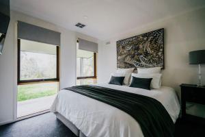 a bedroom with a large bed and a large window at Park Crescent - Daylesford Macedon Region in Kyneton