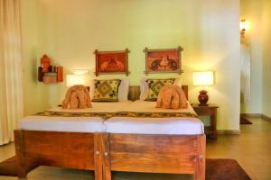 a bedroom with a wooden bed with two horse paintings on the wall at Villa Svara in Kosgoda