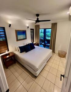 a bedroom with a large white bed with blue pillows at Anchorage in Hamilton Island