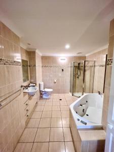 een badkamer met 2 wastafels, een bad en een toilet bij Anchorage in Hamilton Island
