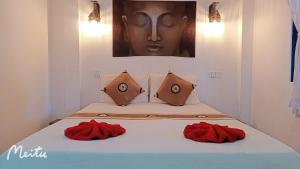 a bed with two red pillows and a painting at Gecko Village in Kampot