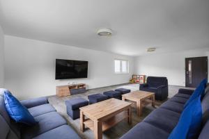 uma sala de estar com sofás azuis e uma televisão de ecrã plano em Holiday House Adam em Prosečné