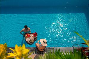 Un homme dans l'eau avec un bol de nourriture dans une piscine dans l'établissement The Oriental Jade Hotel, à Hanoï