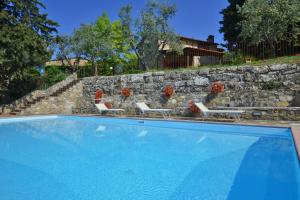 einen Pool mit 2 Stühlen und einer Steinmauer in der Unterkunft La Badia - Happy Rentals in Tavarnelle in Val di Pesa