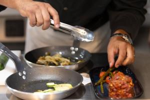 a person is preparing food in a frying pan at Crowne Plaza - Marseille Le Dôme in Marseille
