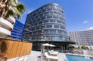 a tall building with a swimming pool in front of it at Crowne Plaza - Marseille Le Dôme in Marseille