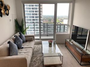 a living room with a couch and a table and large windows at QQ MARKHAM condo in Markham