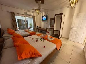 sala de estar con 2 camas con almohadas de color naranja en Villa Authentique, en La Digue