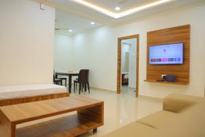 Habitación con cama, mesa y TV. en Padma Homes Stay- Luxury Service Apartment 1BHK & 2BHK & 3BHK, en Tirupati