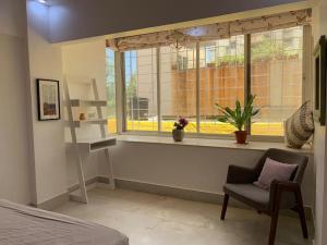 a bedroom with a window with a chair and a chair at Mon Desire 1, Perry Cross Rd, Bandra West by Connekt Homes in Mumbai
