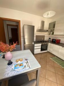 cocina con mesa y nevera de acero inoxidable en "Coccole nel borgo" 2min to outlet apartment with terrace, en Serravalle Scrivia