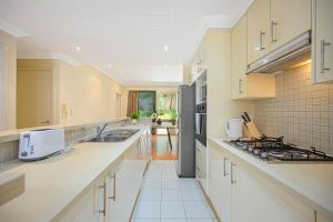 a large kitchen with white counters and appliances at Marsfield New Modern Townhouse in Sydney