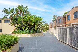 a sidewalk with a fence and some plants at Marsfield New Modern Townhouse in Sydney