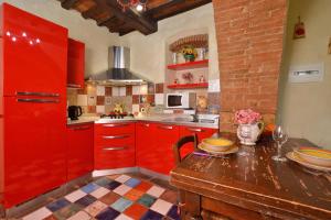una cucina con armadi rossi e tavolo in legno di La Badia - Happy Rentals a Tavarnelle in Val di Pesa
