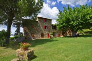 ein Steinhaus mit roten Fenstern im Hof in der Unterkunft La Badia - Happy Rentals in Tavarnelle in Val di Pesa