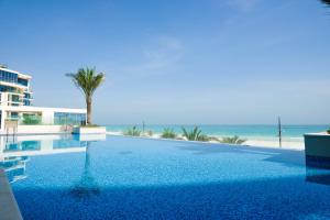 a swimming pool with a palm tree and the beach at Voyage 5 Star Mamsha With Ocean Views in Abu Dhabi