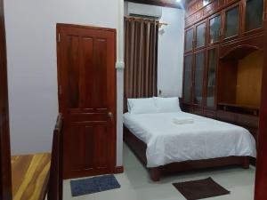 a small bedroom with a bed and a wooden cabinet at Inthavong Hotel/Guest House in Vang Vieng