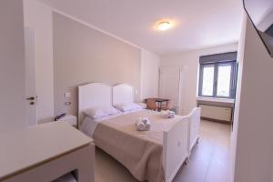 a white bedroom with two beds and a window at Al Rayyan - Affittacamere in Montesano Salentino
