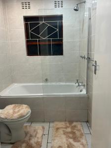 a bathroom with a tub and a toilet and a window at Home away from Home in East London