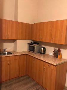 a kitchen with wooden cabinets and a microwave on a counter at Apart-Hotel City Center Contrabas in Lviv