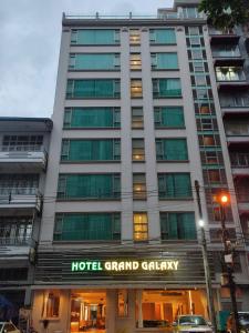 un gran edificio Calgary del hotel con un cartel en Hotel Grand Galaxy en Yangón