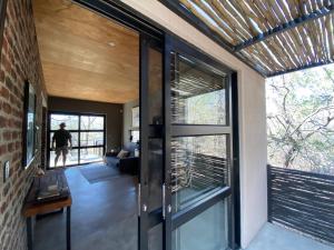 a glass door in a house with a person walking through it at Terrapin Studio in Marloth Park