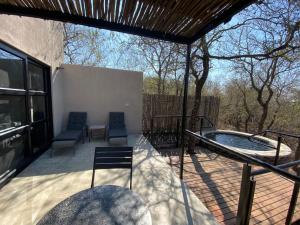 a patio with a hot tub and two chairs at Terrapin Studio in Marloth Park