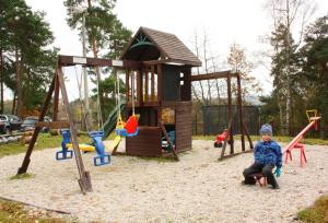 a child sitting on a swing in a playground at Glamping Hnačov 